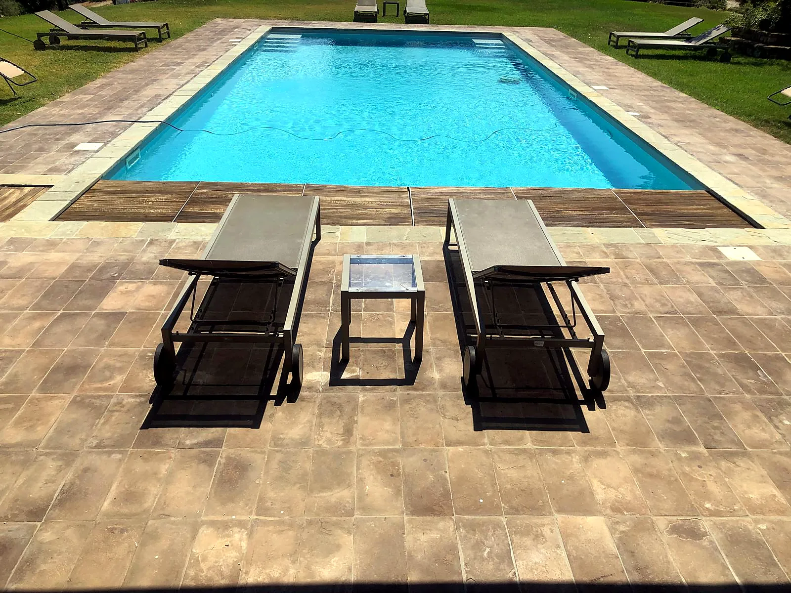 Piscina curata con pedana in legno e lettini
