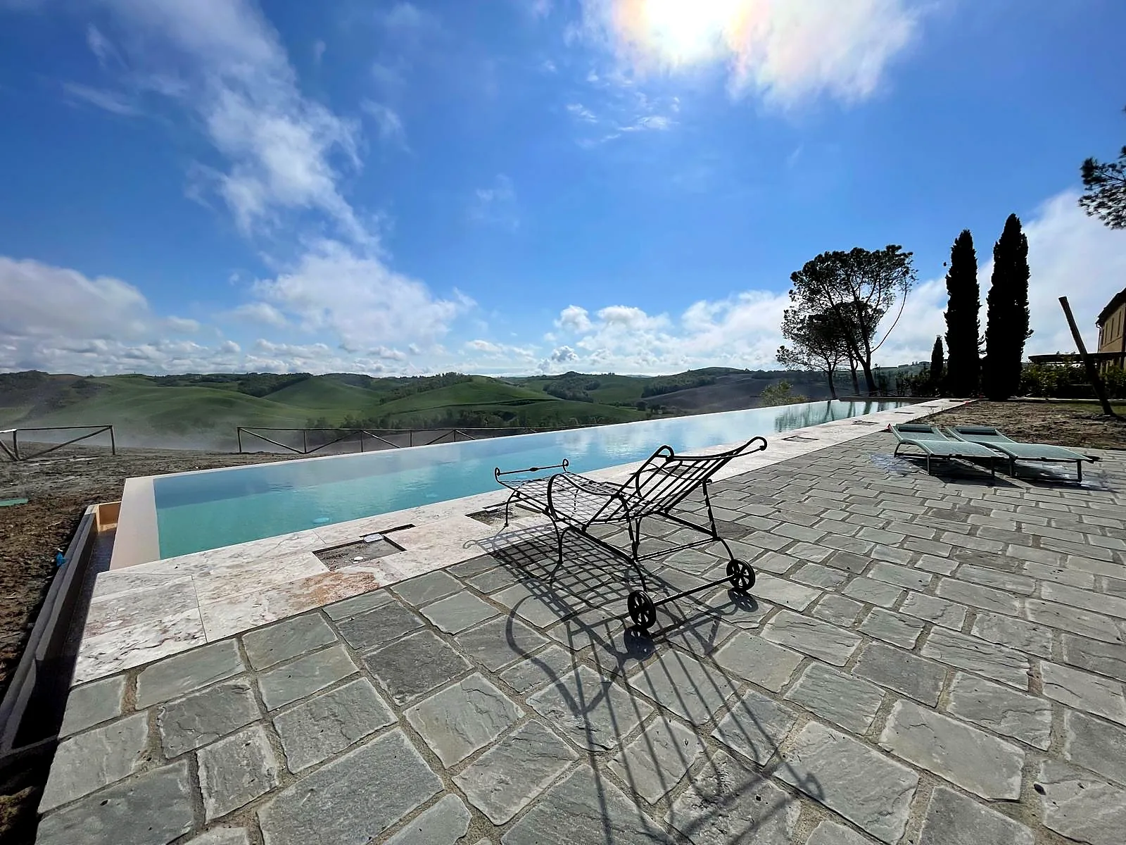 Piscina a sfioro con solarium in pietra e vista sulle colline